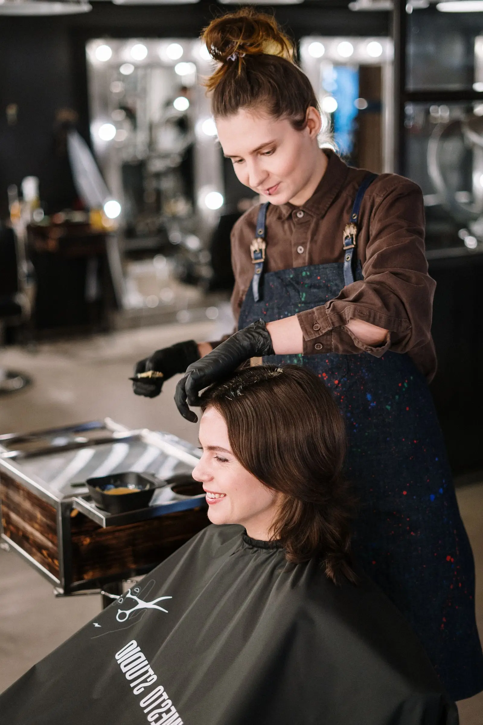 Coloriste appliquant une couleur sur les cheveux d’une cliente dans un salon de coiffure